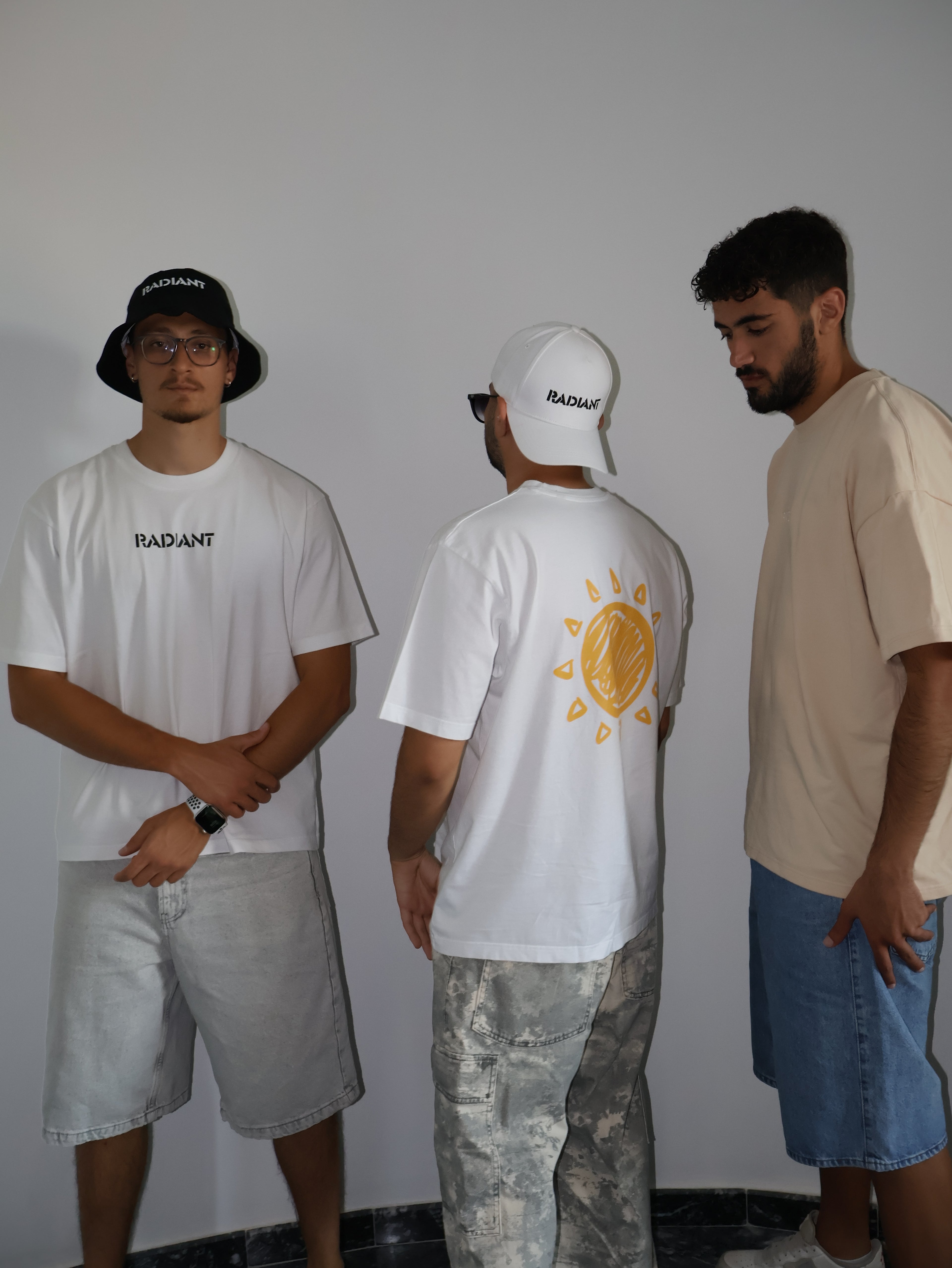 Three people wearing branded t-shirts with a plain background